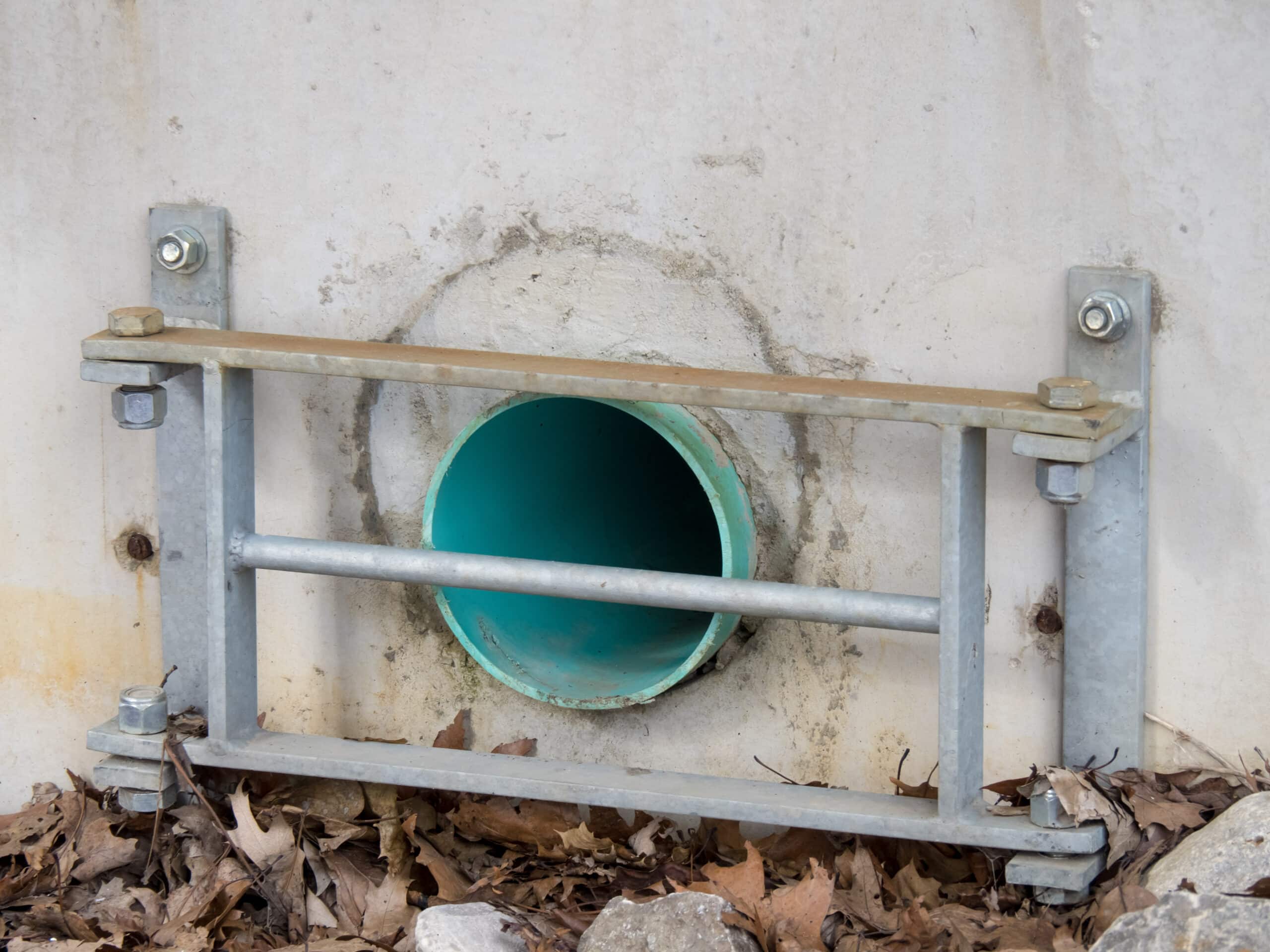a green plastic pipe storm drain outlet with a metal grate